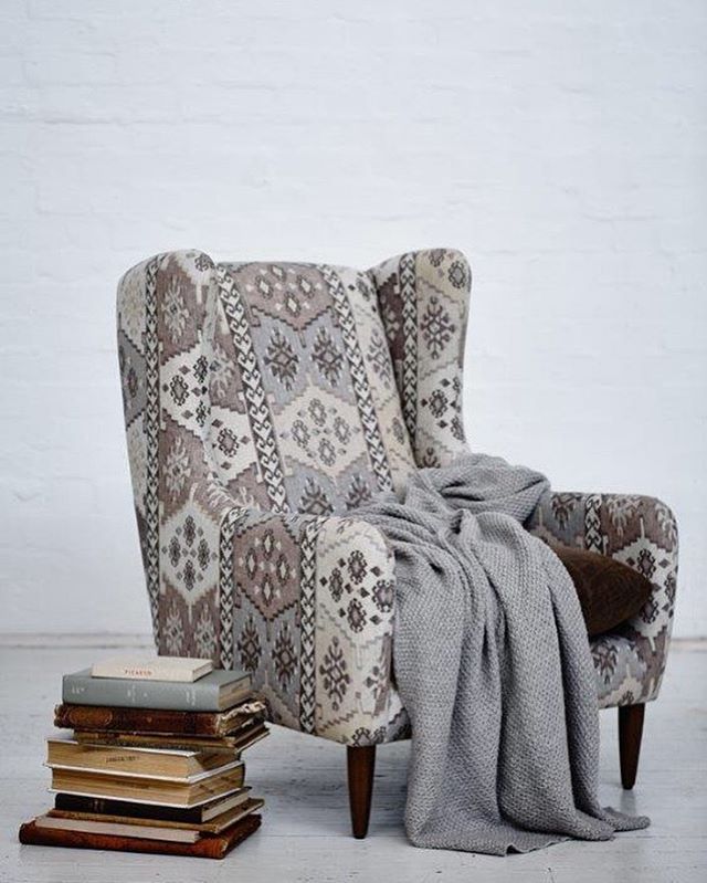 reading chair in with grey throw and books beside brightly patterend
